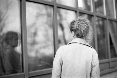 Rear view of woman looking through window