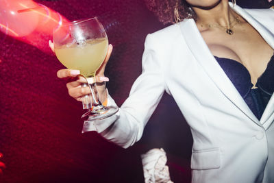 Unrecognizable ethnic woman with goblet of alcohol drink having fun during party in nightclub