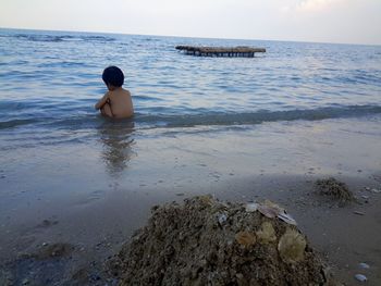 Rear view of man on beach against sky