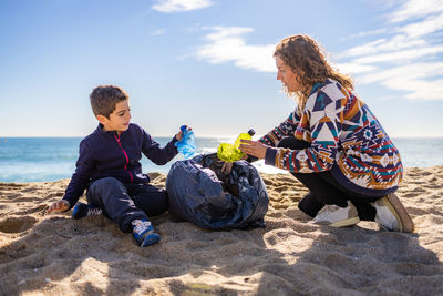 Mother and son picking plastic and garbage on the beach