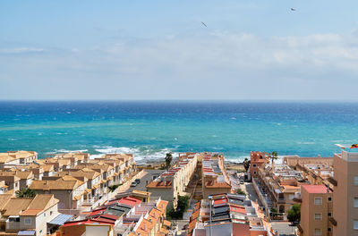 High angle view of buildings by sea against sky