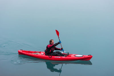 Man holding red boat in sea