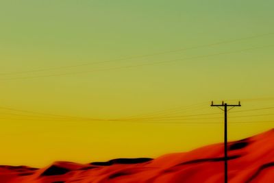 Power lines against sky at sunset