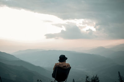 A man is sitting  on the peak and looking at the sky 