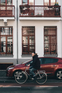 Man riding bicycle on street against building
