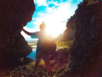 People standing on rock by sea against sky