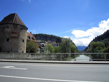 Road by buildings against blue sky