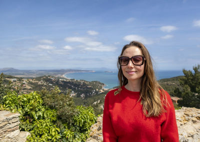 Portrait of smiling woman standing against sky