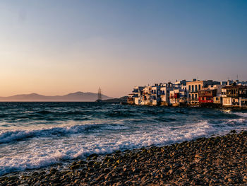 Residential district by sea against sky during sunset
