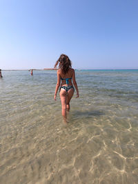 Full length of woman on beach against clear sky