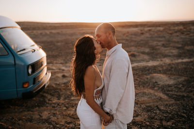 Woman standing on land against sky during sunset