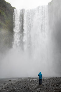 Rear view of man looking at waterfall