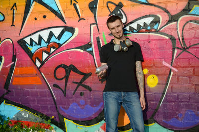 Full length of young man standing against graffiti wall