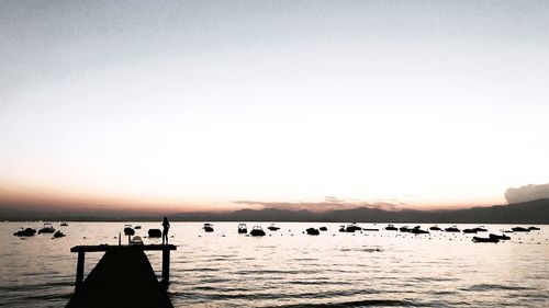 Silhouette people swimming in sea against clear sky