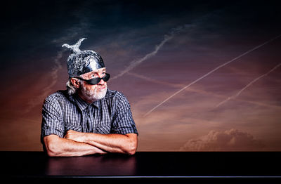Man looking away while wearing foil hat against sky
