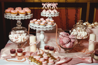 Cupcakes with pink cream and decorated with golden pastry beads on a white tray