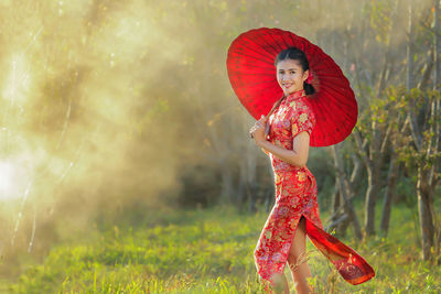 Woman with red umbrella on field