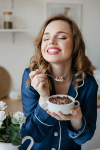 Portrait of young woman having food at home