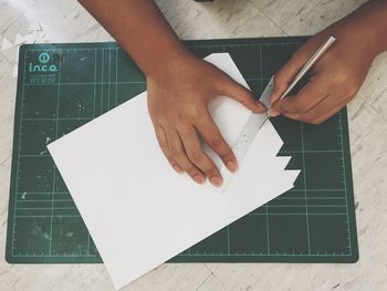 Close-up of hand holding paper with text on table