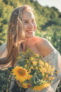 Portrait of smiling young woman with yellow flower