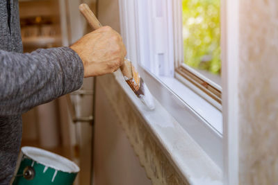 Midsection of man holding window at home