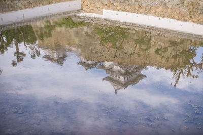 Reflection of clouds in puddle on lake