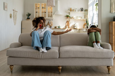 Annoyed unhappy african american mother talking on phone complaining about son behavior