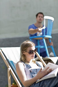 Young woman reading, man in background painting, stockholm, sweden