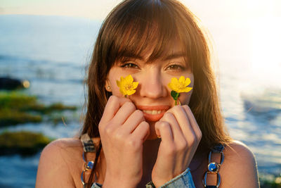 Portrait of a young woman holding flowers near her face