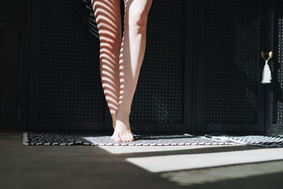 Bare feet of young woman in the bathroom at home, light and shadow person