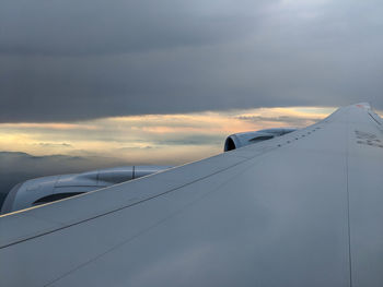 Airplane flying in sky at sunset