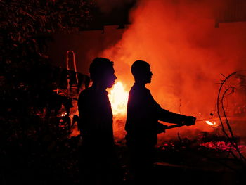 Silhouette people against fire at night