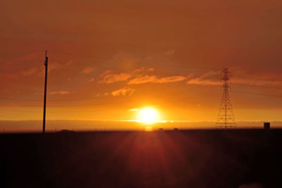 Silhouette electricity pylon against sky during sunset