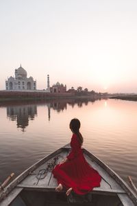 Rear view of woman on lake against sky during sunset