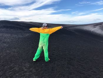 Rear view of woman in protective workwear standing on mountain against sky