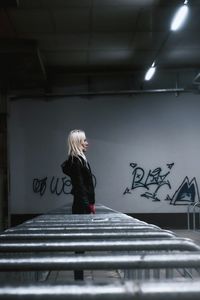 Side view of woman standing against wall