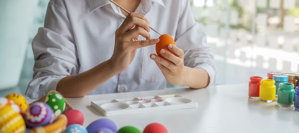 Midsection of woman holding multi colored bottles on table