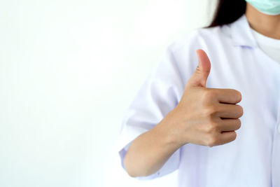 Midsection of female doctor gesturing against wall