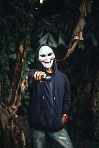 Man wearing mask in forest at night