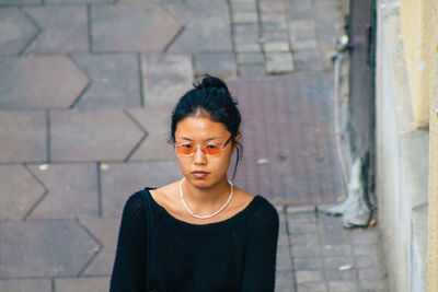 Portrait of beautiful woman standing against brick wall