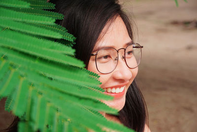 Young woman wearing eyeglasses while looking away by plants