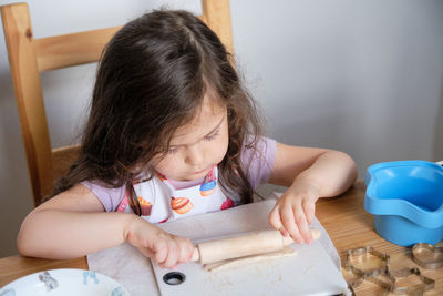 A young girl is playing chef at the kitchen table.