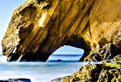 Rock formation in sea against sky