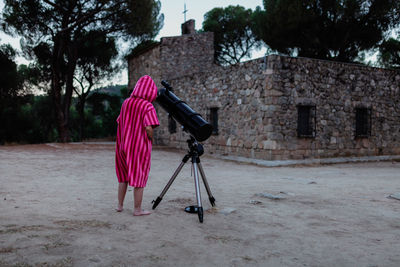 Woman photographing with umbrella on building