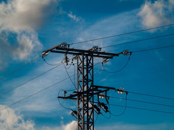 Low angle view of electricity pylon against blue sky