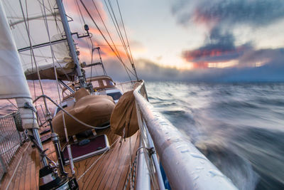 Sailboat sailing on sea against cloudy sky during sunset