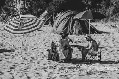 Rear view of people sitting on chair at beach