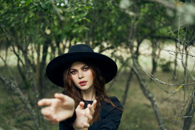Young woman wearing hat standing against trees
