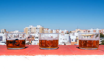 Close-up of a three glass of beer with a city in the background