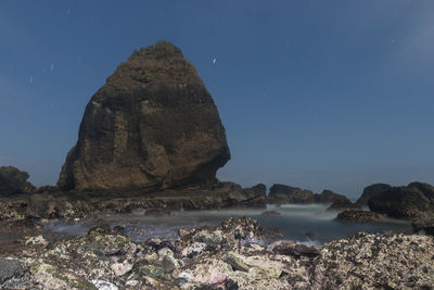 Rock formation on beach against clear sky